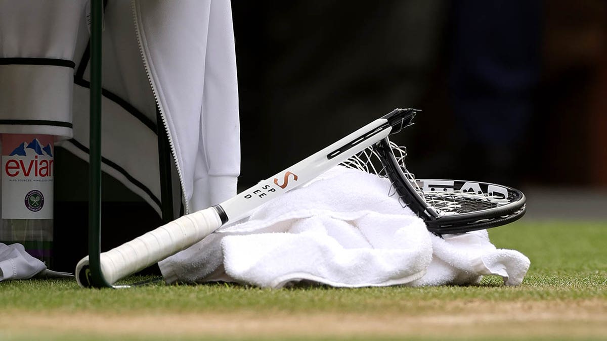Novak Djokovic holding a smashed tennis racket during a match at Wimbledon.