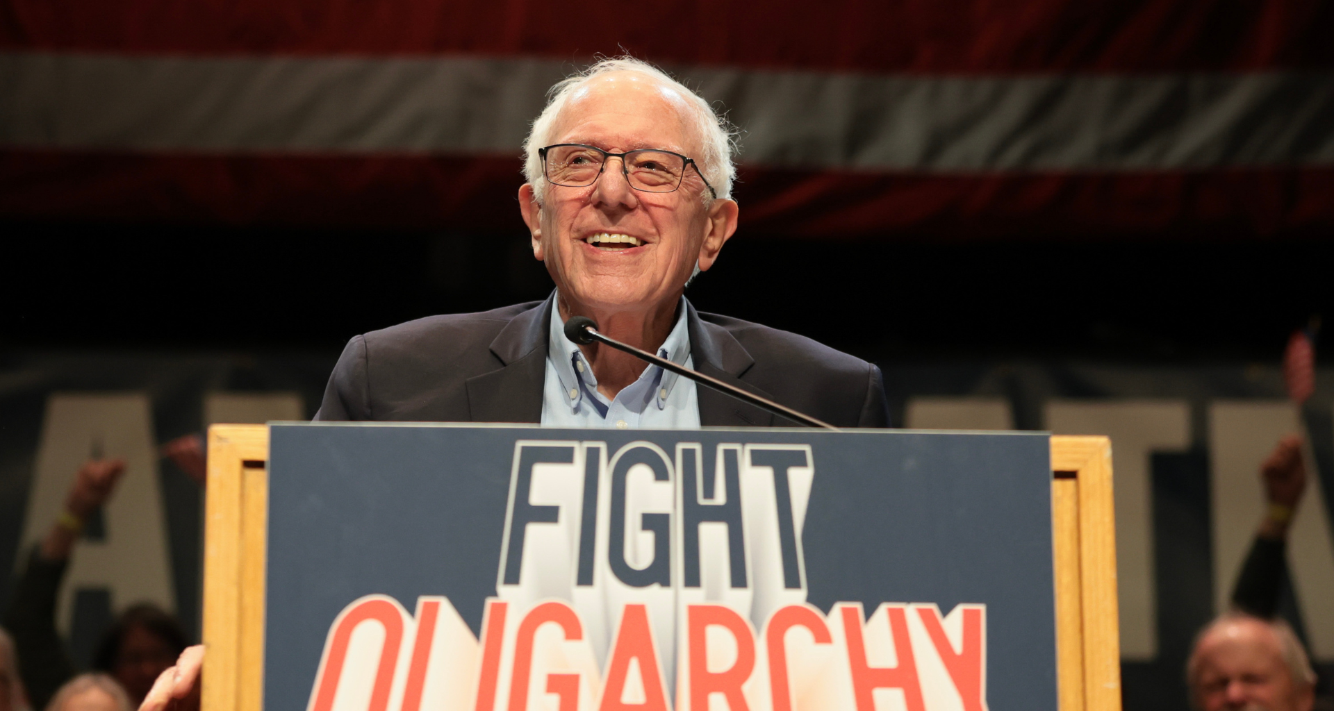 Bernie Sanders on a podium with a Fight Oligarchy sign