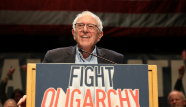 Bernie Sanders on a podium with a Fight Oligarchy sign