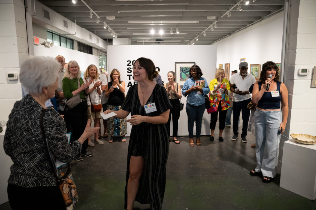 GFAA Executive Director Katy Lemle (center) presenting Jane Polkowski (left) an award for her artwork Self Portrait with Toulouse being selected as Best in Show.