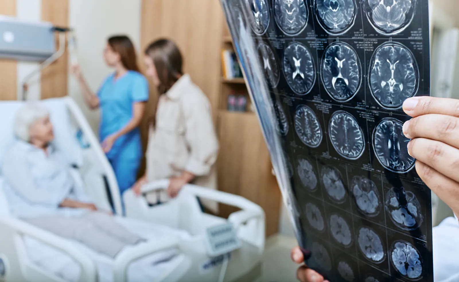A stock image shows an MRI of the head of an elderly woman in the hands of a doctor in a medical ward.