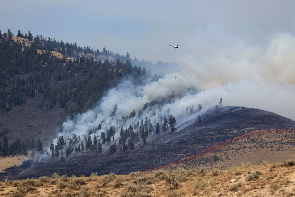 A helicopter crew battles a wildfire near Kalispell, Mont., in August 2022. Credit: Don and Melinda Crawford/Universal Images Group via Getty Images
