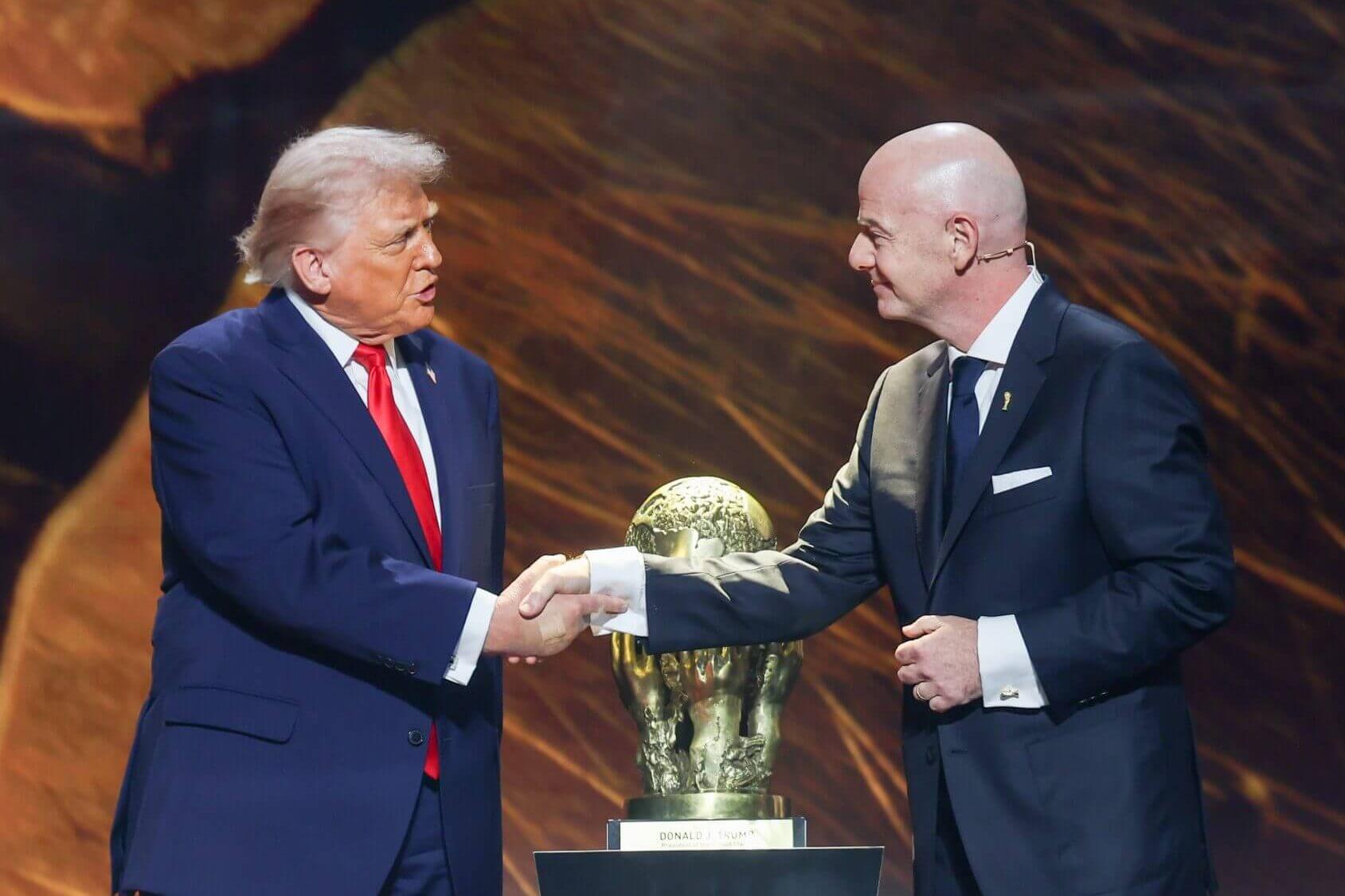 Two men shake hands in front of a golden trophy