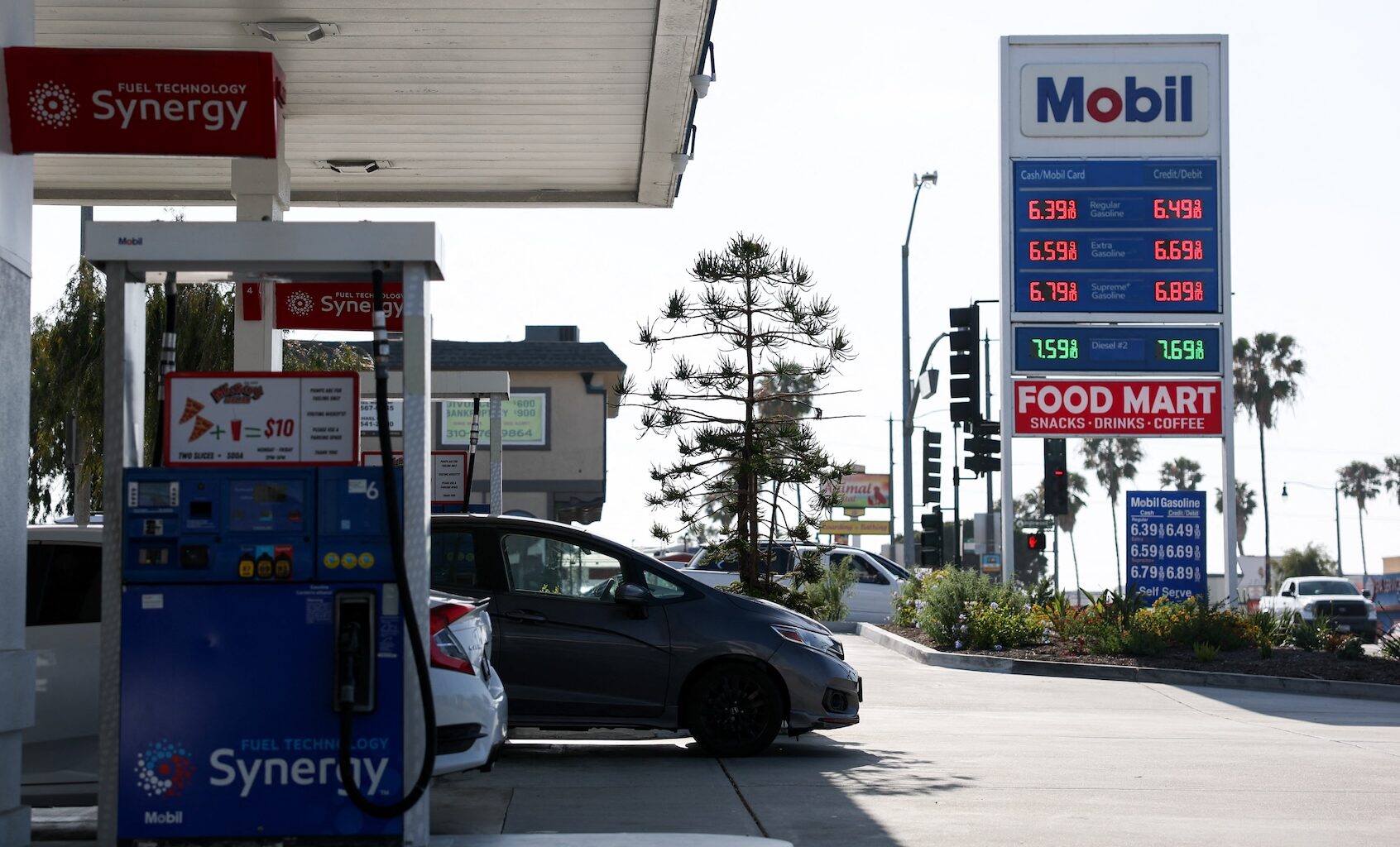 Vehicles sit parked at fuel pumps as regular gasoline prices above $6 per gallon and diesel prices above $7 per gallon are displayed outside a Mobil gas station in Redondo Beach, California on April 30, 2026. (Photo by Patrick T. Fallon/Getty Images)