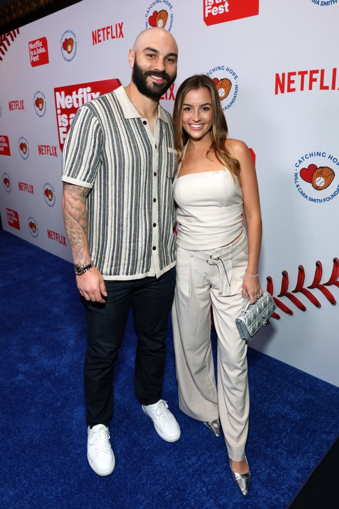 A bald man with a beard and a woman with long brown hair pose on a blue carpet with Netflix and Catching Hope Foundation logos.