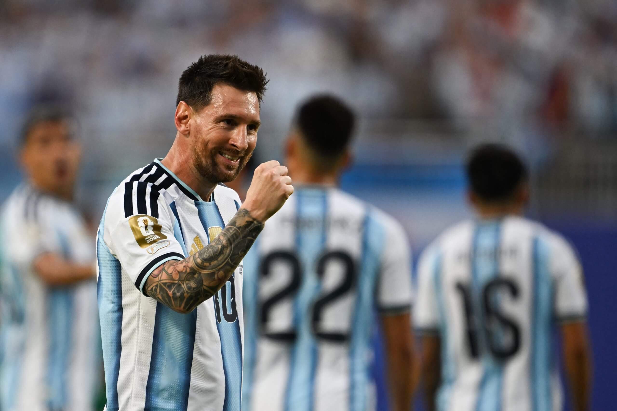 Argentina's forward Lionel Messi celebrates scoring against Algeria. Wearing the traditional sky blue and white striped kit, he is clenching his right first