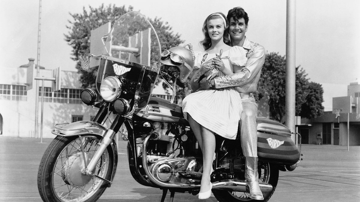Ann-Margret as Kim McAfee and Jesse Pearson as Conrad Birdie seated on a motorcycle in a film scene.