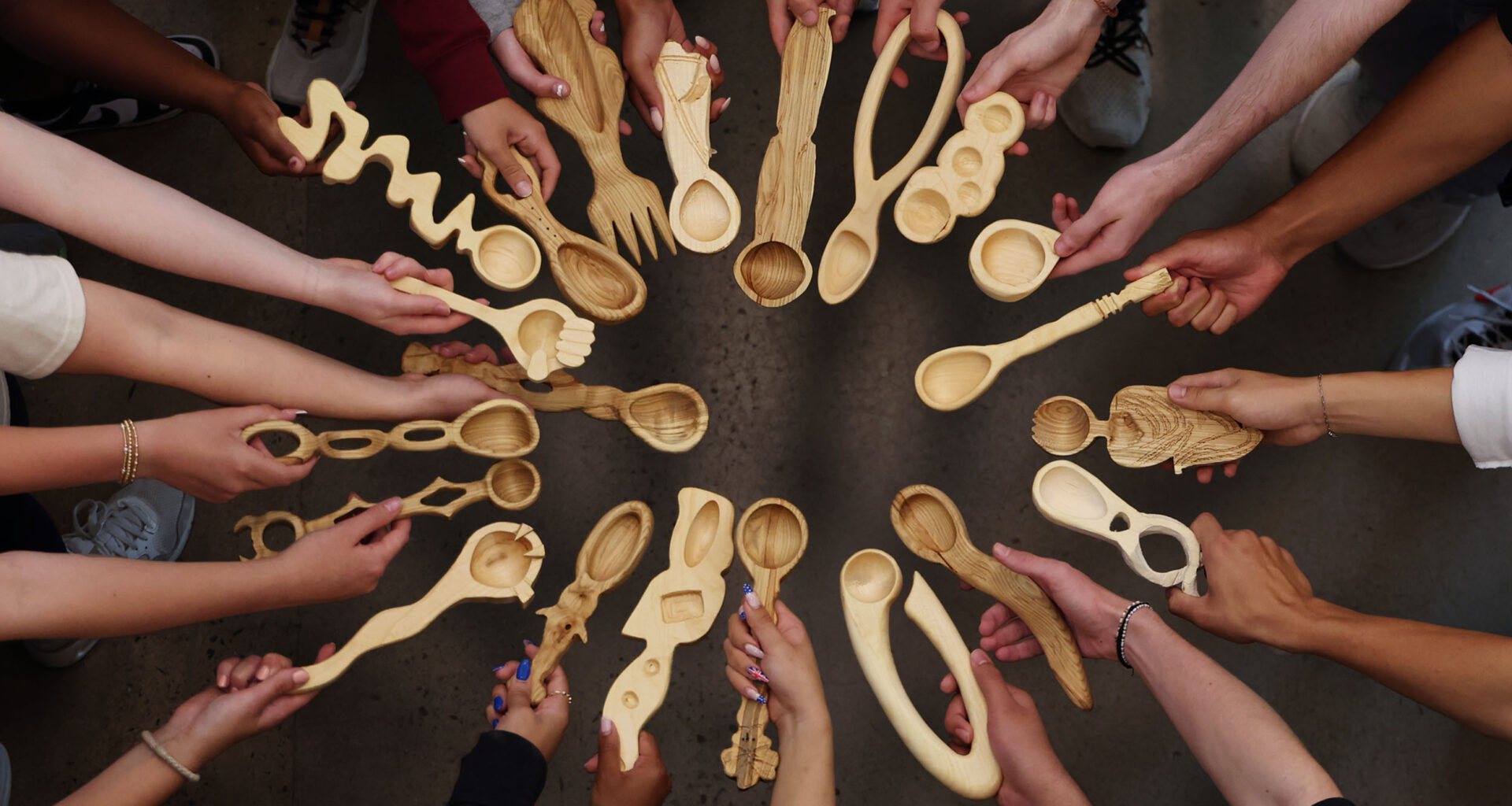 Students standing in a circle holding out their spoons.