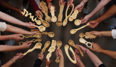 Students standing in a circle holding out their spoons.