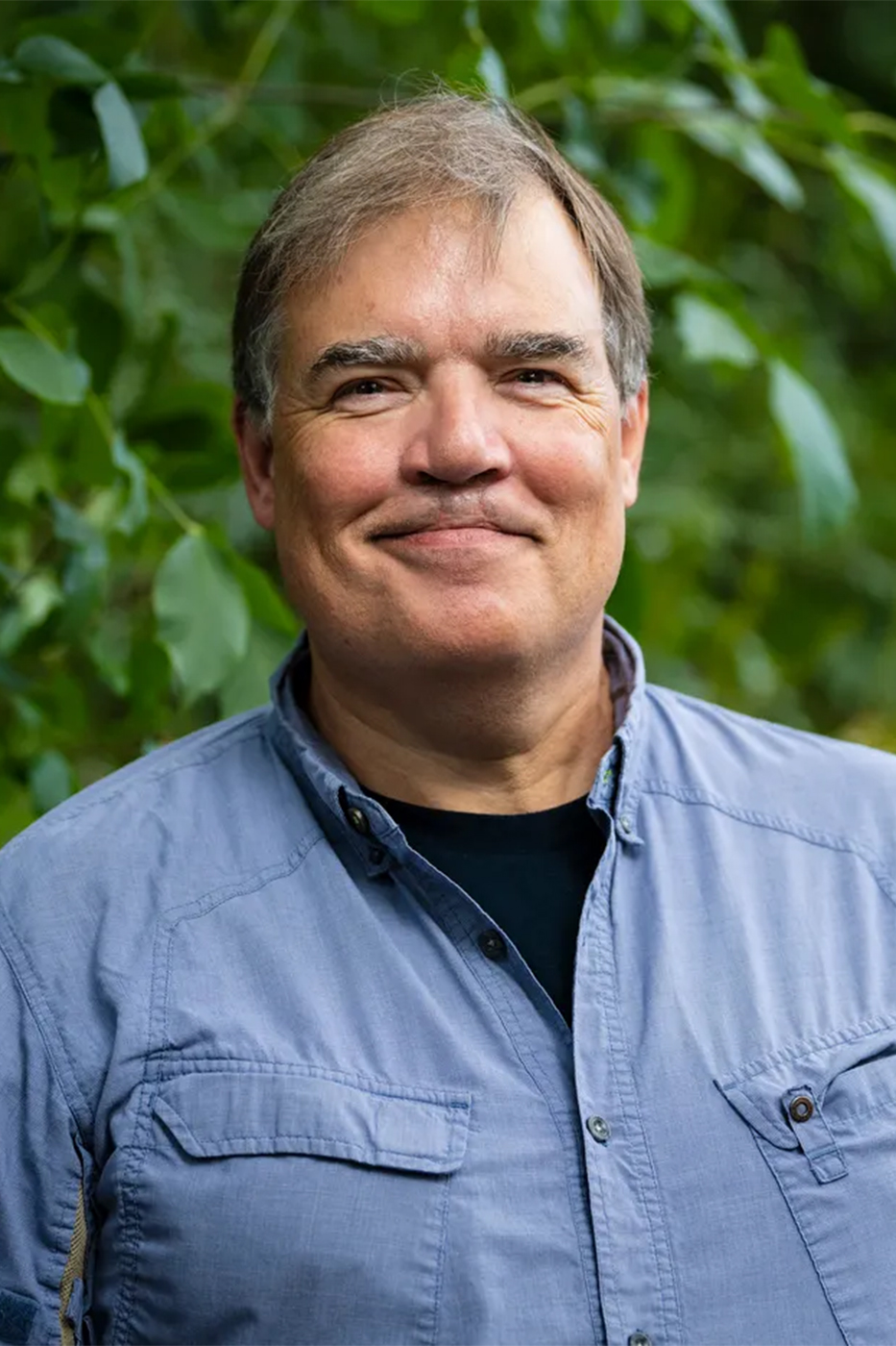 Brian Helmuth, professor of marine and environmental sciences at Northeastern University, photographed outdoors against a backdrop of green foliage.