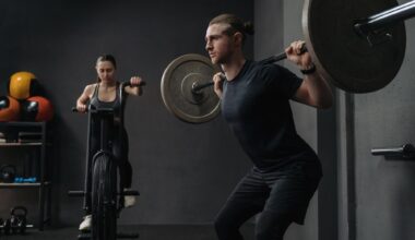 Fit woman is working out on exercise bike, while muscular man training with barbell.