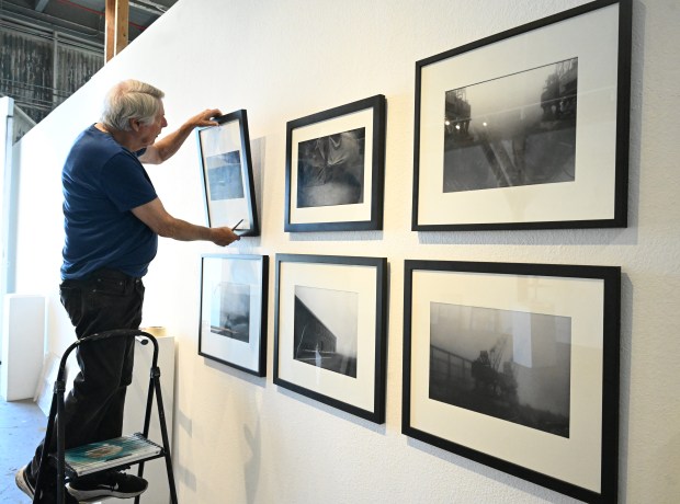 Jerry Downs helps to hang photographs that are part of the Wendy the Welder & The Mare Island Shipyard Workers show opening at Mare Island Art Studios on Sunday. (Chris Riley/Times-Herald)