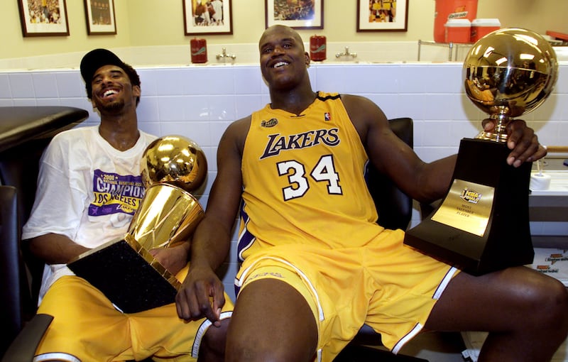 Shaquille O’Neal is pictured here holding his Most Valuable Player trophy and smiling next to his teammate Kobe Bryant after they won the NBA Finals in 2000.