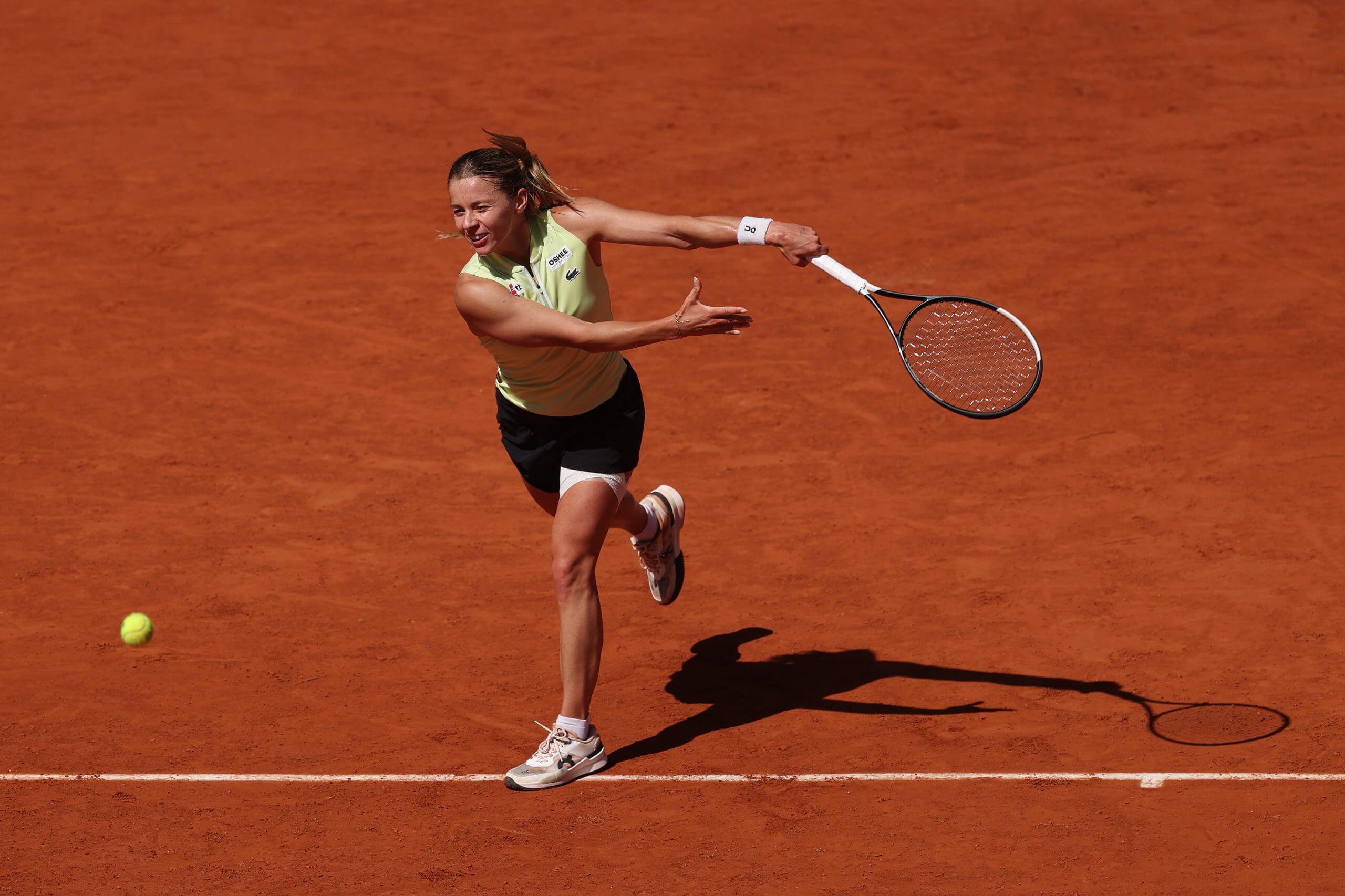 Maja Chwalińska follows through on a backhand slice on a clay tennis ocurt.