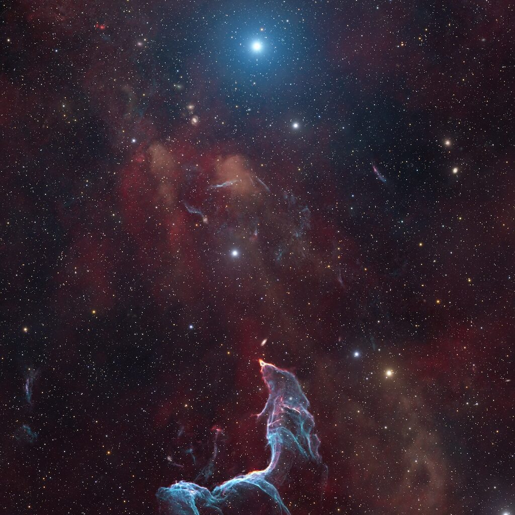 A delicate nebula in shades of blue and purple
	  shines in front of a dark field of stars.
	  The shape of the nebula resembles a mermaid.