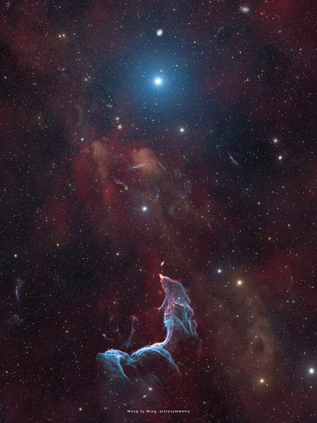 A delicate nebula in shades of blue and purple
shines in front of a dark field of stars.
The shape of the nebula resembles a mermaid.