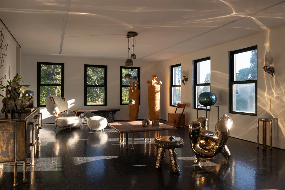 Sunlit modern living room with unique sculptures, eclectic furniture, and large windows casting artistic shadows on the floor.