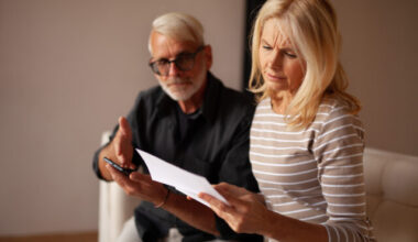 Older couple looking concerned at a document and cellphone