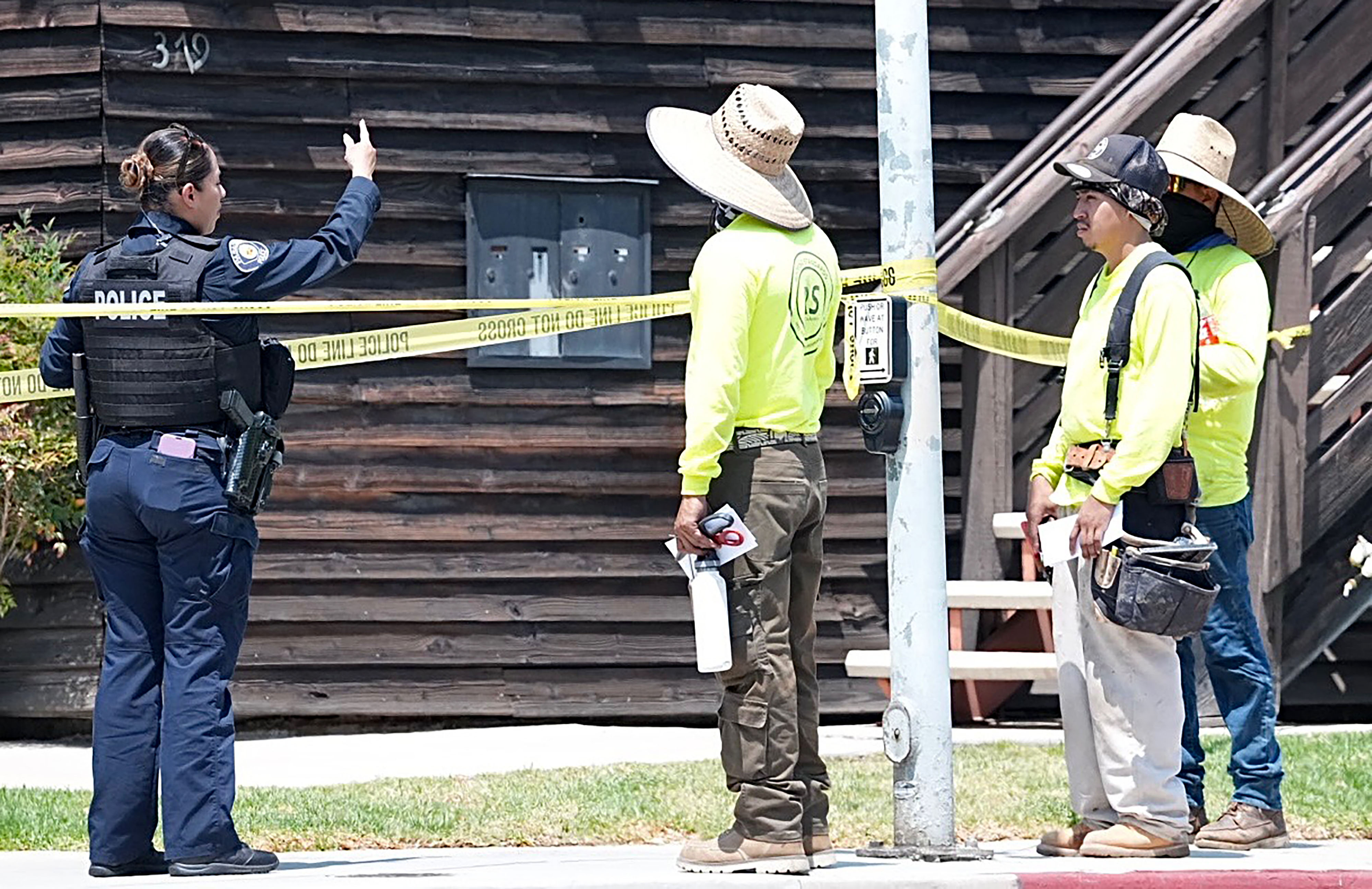 A police officer speaks with construction workers near the scene...