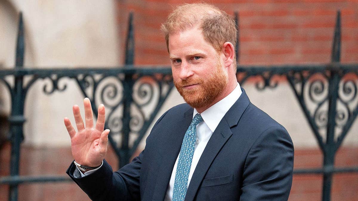 Prince Harry waving a dark blue suit waving in London.