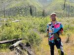 FILE - Eli Tome stands on an island at Finn Rock Reach on May 18, 2026. A sapling ponderosa tree is to his right, and surrounding lupine and willows have grown tall this year.