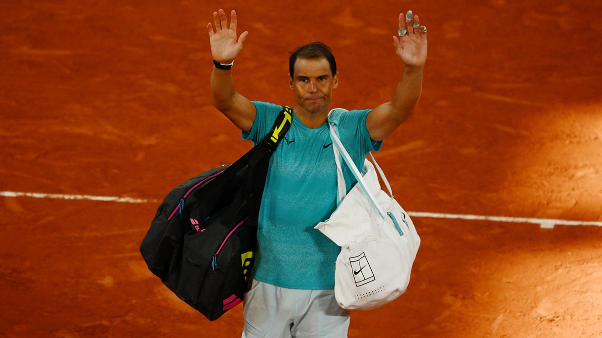 Rafael Nadal waving to crowd walking off tennis court at French Open