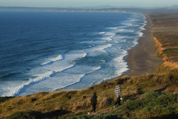 A pair of hikers walk along the hillside overlooking Point Reyes Beach in Inverness on Wednesday, Nov. 8, 2023. The Point Reyes National Seashore is the starting point of the American Discovery Relay 250, which invites volunteers to take on connecting trails to cross the U.S. starting on July 1, 2026. (Jose Carlos Fajardo/Bay Area News Group)