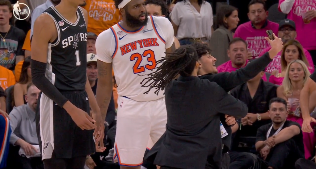 Victor Wembanyama and Mitchell Robinson watch as a fan runs onto the court.