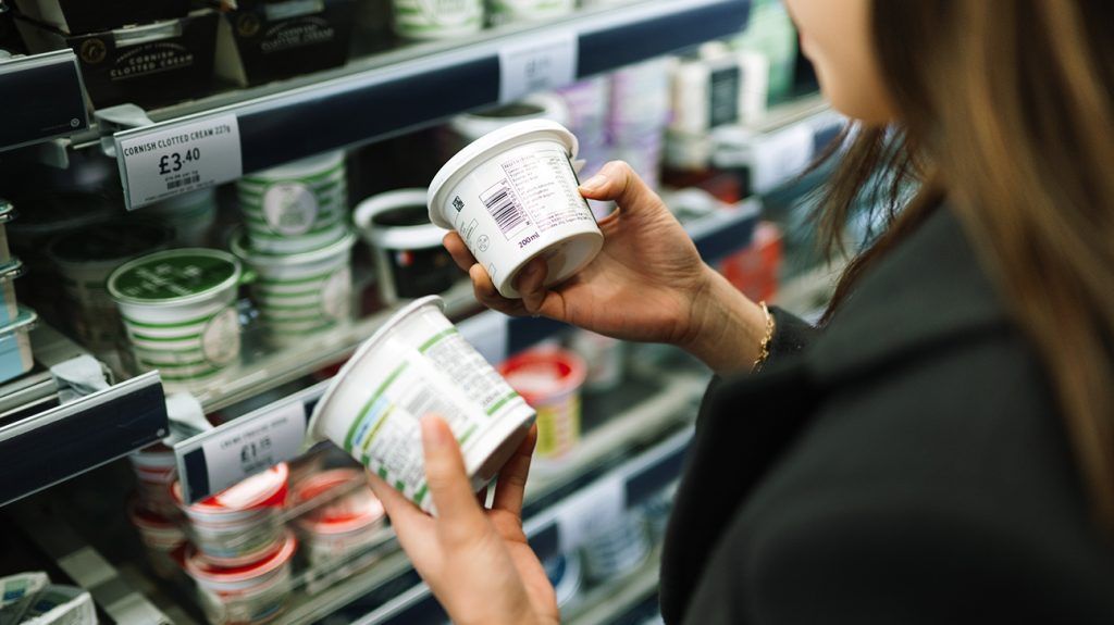 person checking ingredients list on food packaging at a store