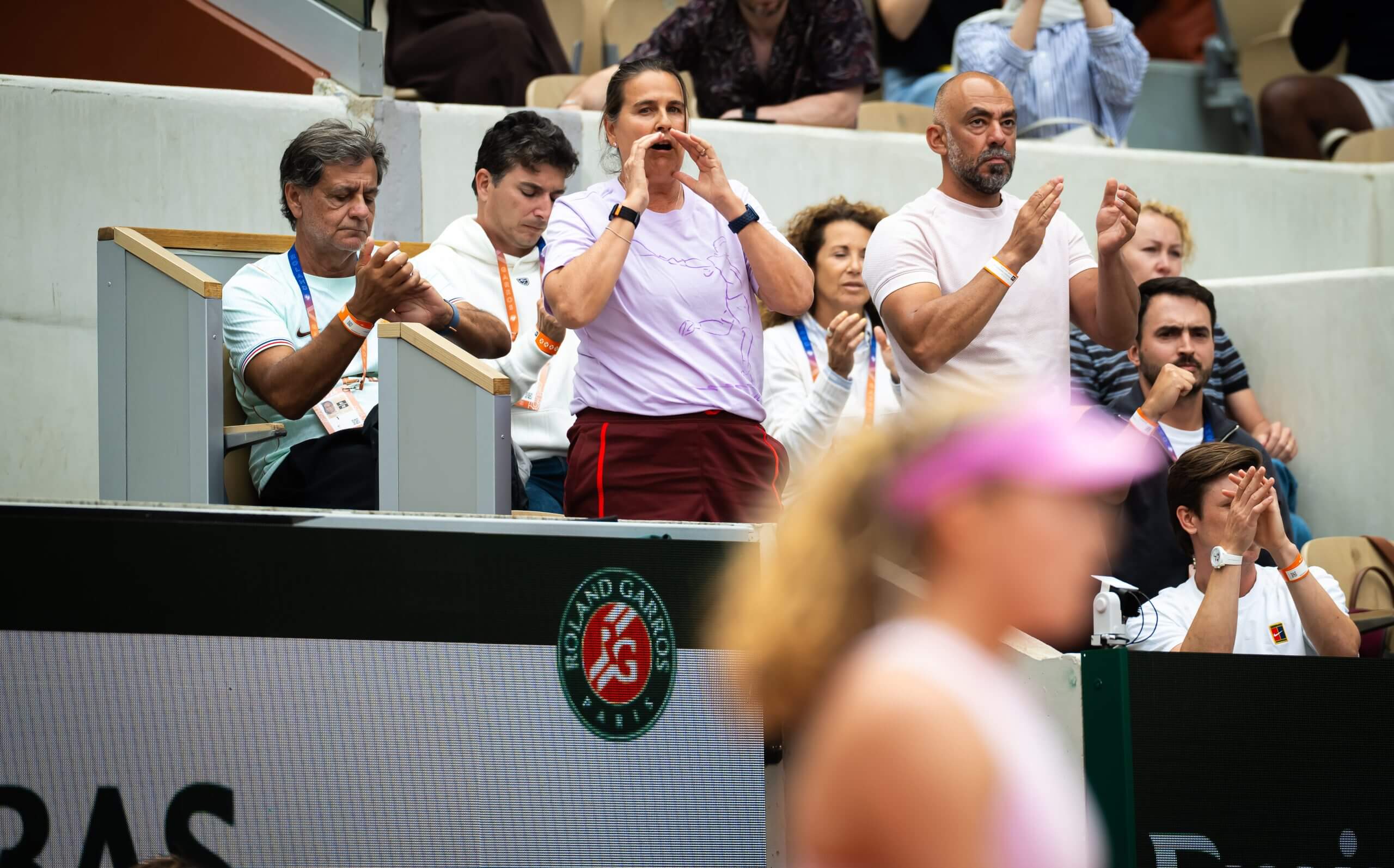 Conchita Martinez communicates with Mirra Andreeva from her box on a tennis court.