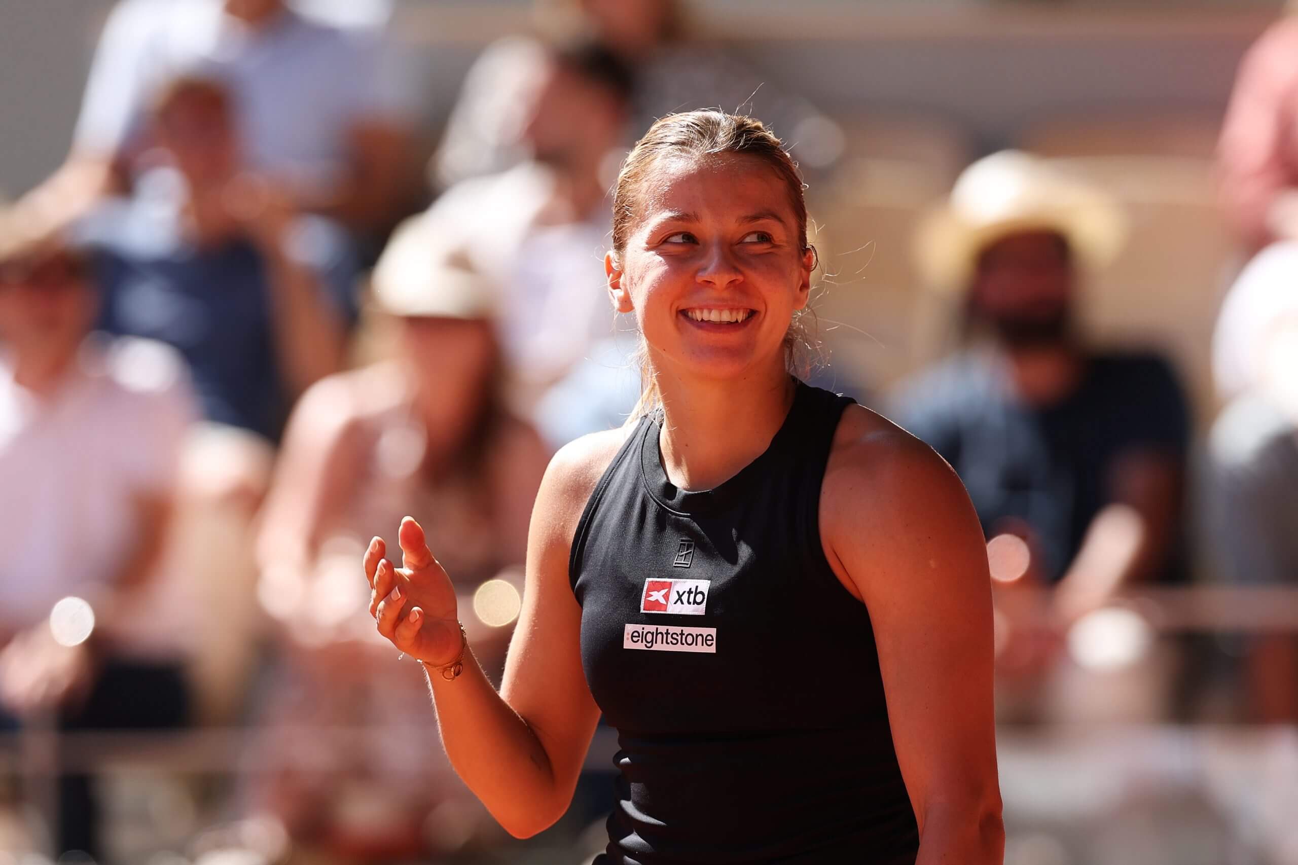 Maja Chwalińska looks on with a smile in front of a crowd.