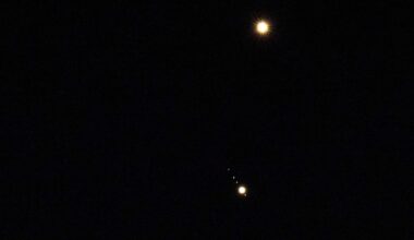 Venus is pictured shining brightly above Jupiter in a black sky. A number of small star-like objects can be seen in a line surrounding Jupiter, representing its four largest Galilean Moons.