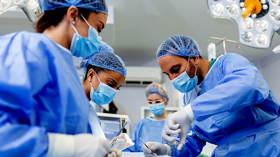 Group of plastic surgeons performing surgery in an operating room with medical equipment