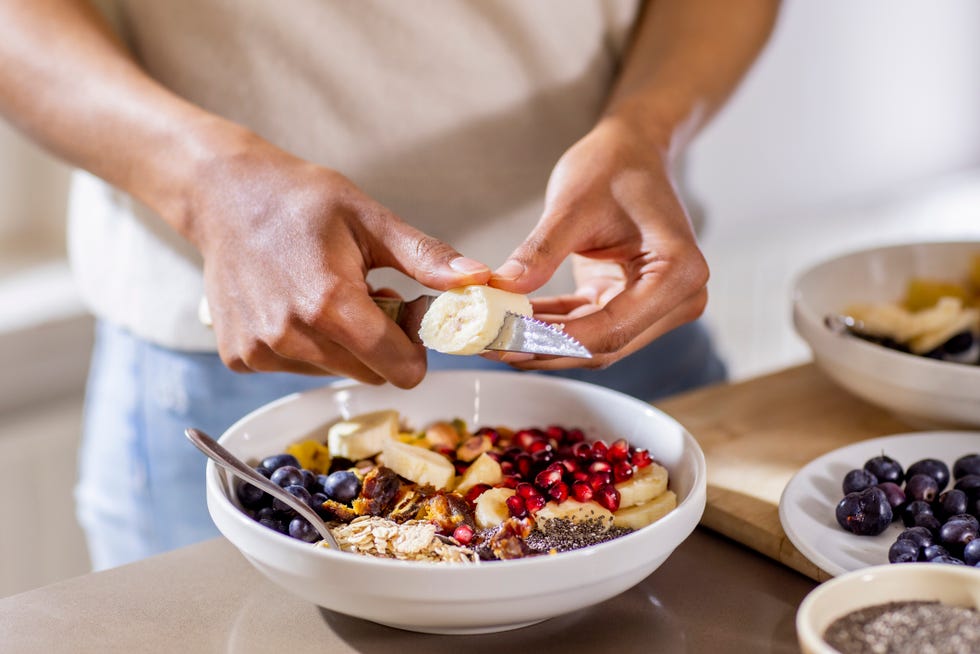close up of woman making healthy breakfast in kitchen with fruits and yogurt close up of woman making healthy breakfast in kitchen with fruits and yogurt