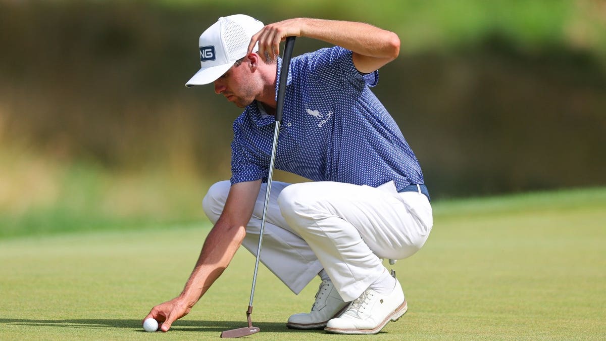 Alex Smalley lining up a putt on the 14th green during a golf tournament.