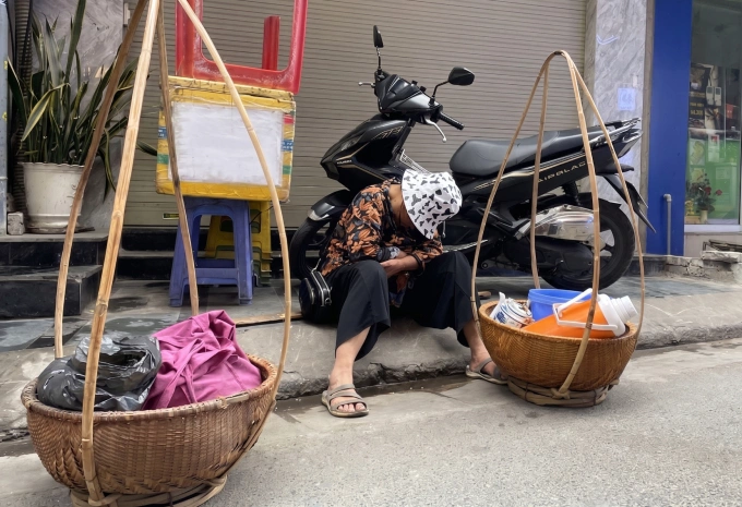 Một người cao tuổi ngủ gục bên gánh hàng rong trên phố Hà Nội, tháng 3/2026. Ảnh: Phan Dương
