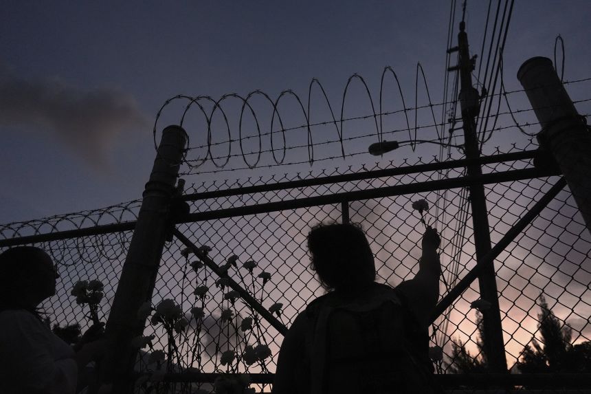 People place flowers on a fence outside Krome Detention Center in Miami, Saturday, May 24, 2025, during a vigil to recognize people who have died in U.S. Immigration and Customs Enforcement custody as well as those affected by mass deportations.