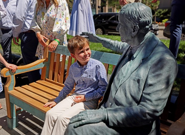 One of Jack Connors Jr.'s grandsons sits on the bench after the unveiling outside the Hancock tower. (Nancy Lane/Boston Herald)
