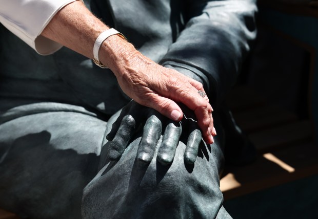 Jack Connors' widow, Eileen, touches the hand of the statue of her husband after the unveiling outside the Hancock tower. (Nancy Lane/Boston Herald)