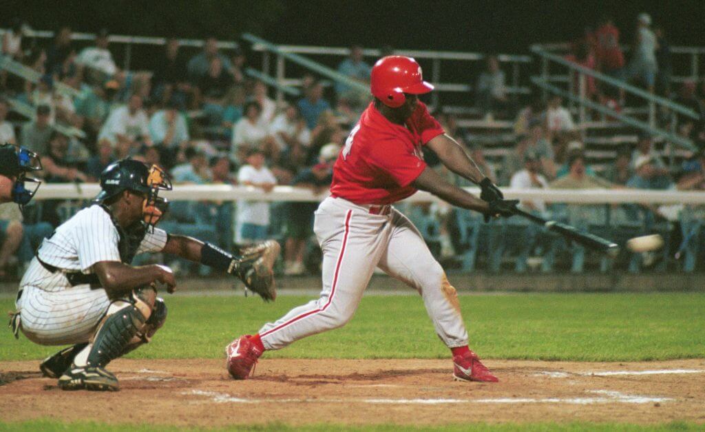 Ricky Williams swings a baseball bat at a pitch