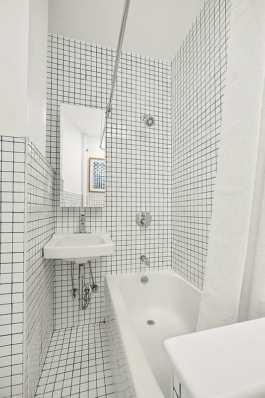 bathroom with square, white wall tile with black grout and white fixtures