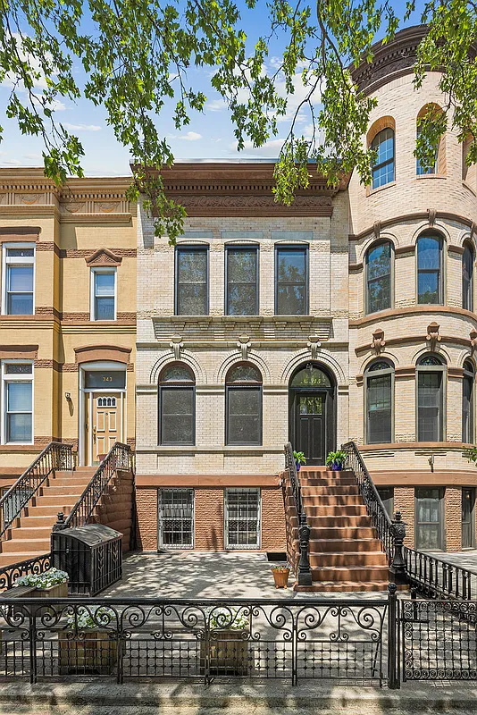 pale brick exterior of a row house with a high stoop and arched, brick details