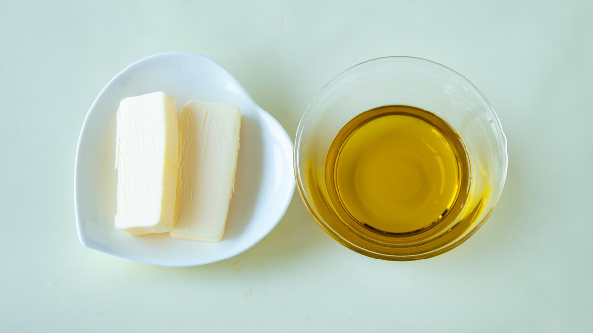 Butter and olive oil side by side on a white surface