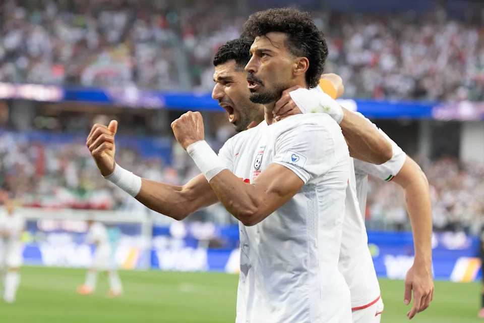 Iran's Mehdi Taremi puts his arm around Ramin Rezaeian as they celebrate a goal during their match against New Zealand on June 15.