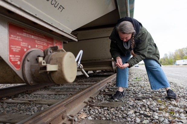 Sherri Mason, a Gannon University researcher, picks up plastic pellets, pieces barely larger than a grain of rice, that litter the ground where they are transferred from rail cars to trucks and delivered to local manufacturers on May 1, 2026, in Erie, Pennsylvania. (Brian Cassella/Chicago Tribune)