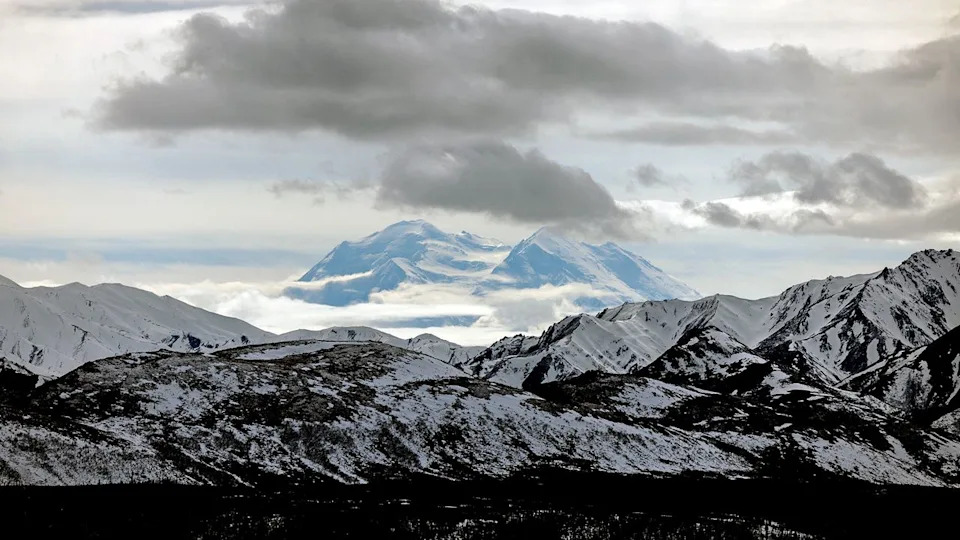 A snowy mountain range under a cloudy sky.