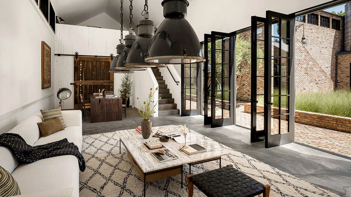 A living room with big doors leading to the yard and a small office space.