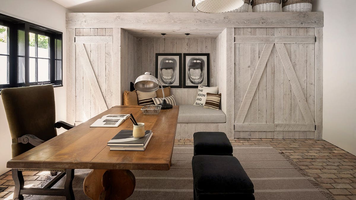 A home office with a gray farmhouse-style accent wall and a lounge area.
