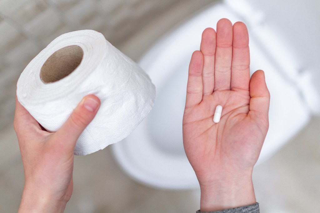 Hands holding toilet paper and a pill, symbolizing diarrhea treatment.