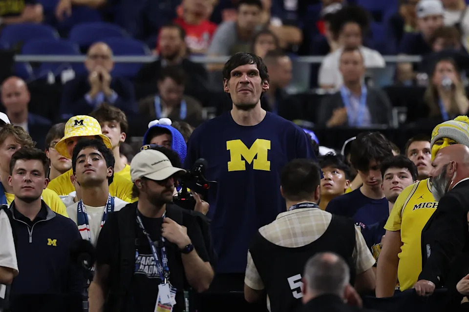 Person in "M" shirt stands out in a crowd at a sports event, surrounded by fans wearing similar team gear